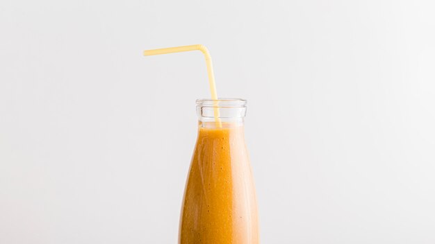 Front view bottle with orange smoothie and straw