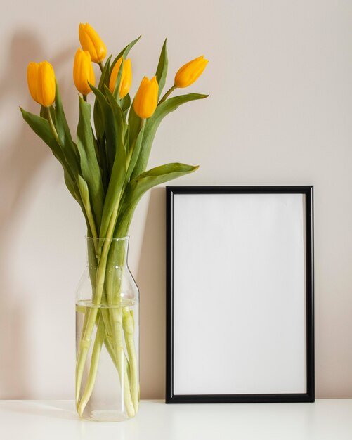 Front view bouquet of tulips in a vase with empty frame