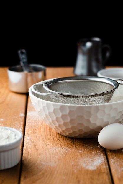 Front view of a bowl and sieve on wooden table