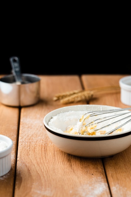 Front view of bowl and whisk on wooden table