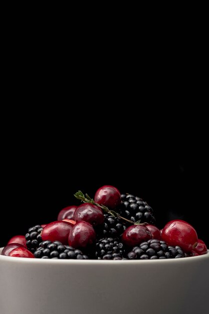 Front view of bowl with cherries and blackberries and copy space