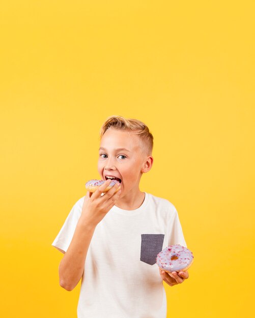 Front view boy eating doughnuts