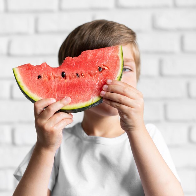 Free photo front view boy eating watermelon