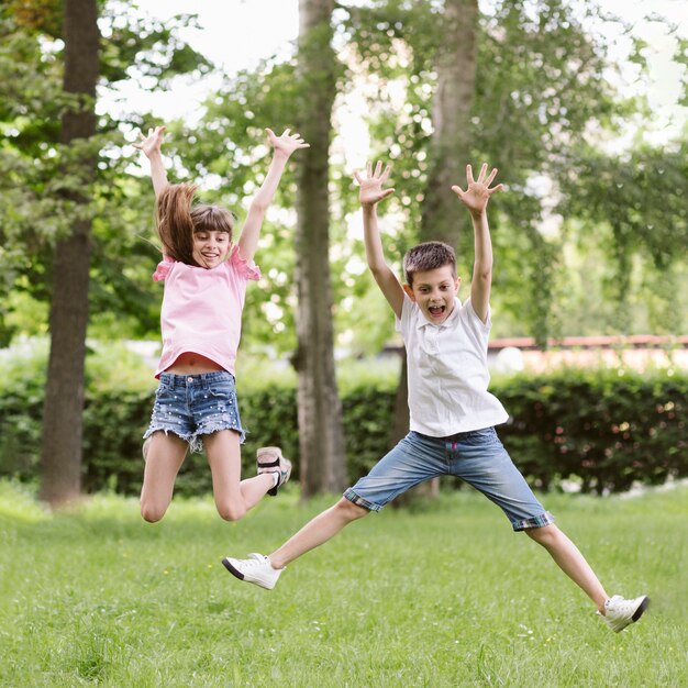 Вид спереди мальчик и девочка прыгает