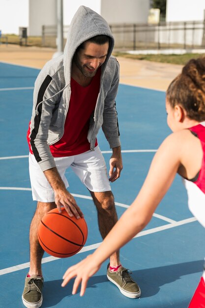 Вид спереди мальчика и девочки играют в баскетбол