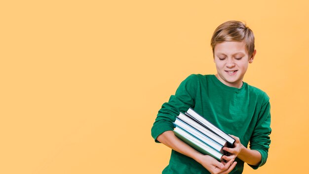 Front view of boy holding books with copy space