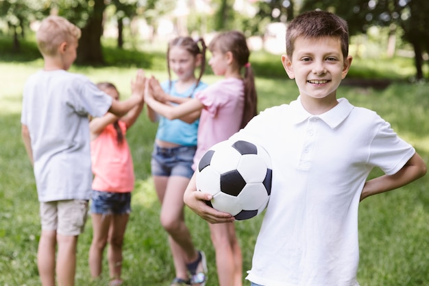 Free photo front view boy holding a football ball