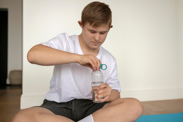 Foto gratuita ragazzo di vista frontale che tiene bottiglia d'acqua