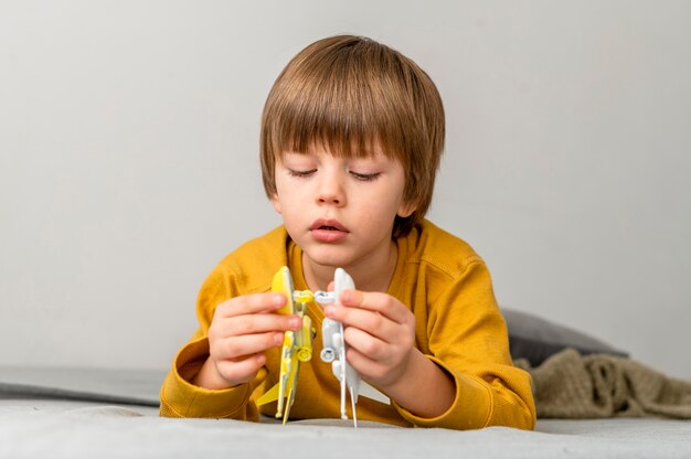 Front view of boy playing with airplane figurines