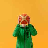 Бесплатное фото Мальчик вид спереди играет с баскетбольным мячом