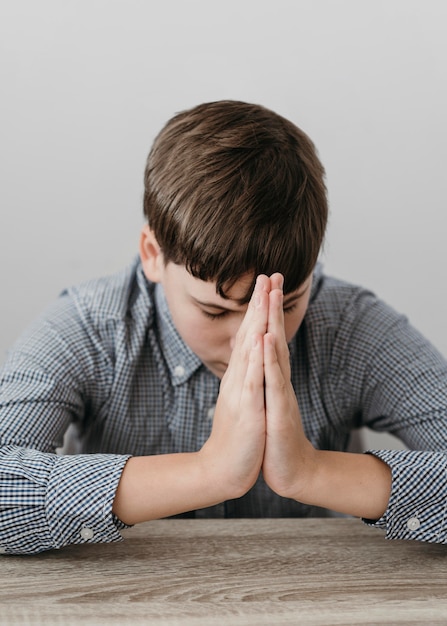 Бесплатное фото Мальчик вид спереди молится дома