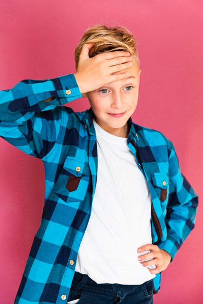 Front view boy standing with one hand at his forehead