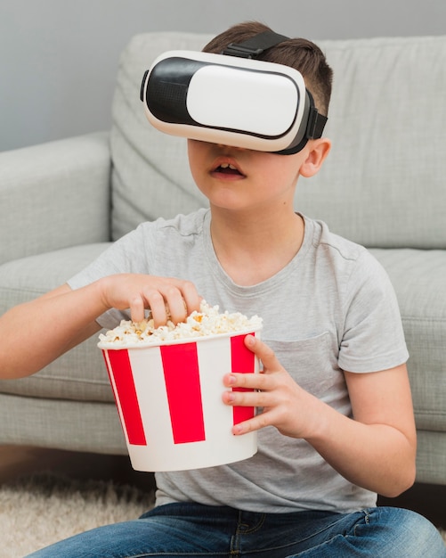 Foto gratuita vista frontale del film di sorveglianza del ragazzo con la cuffia avricolare di realtà virtuale e avere popcorn