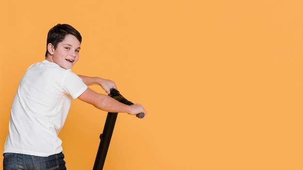 Free photo front view of boy with scooter with copy space