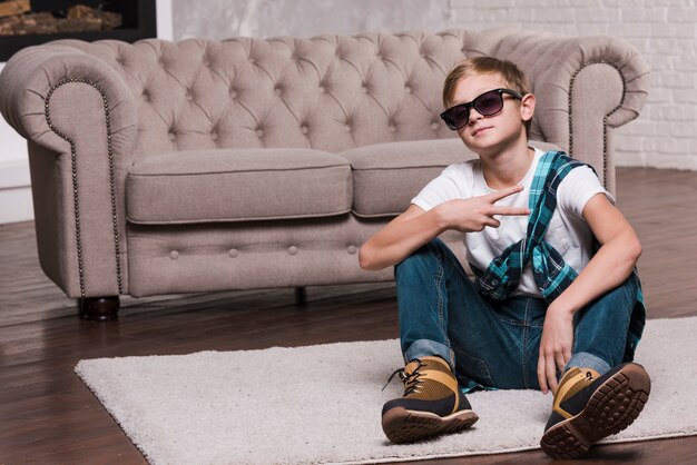 Front view of boy with sunglasses sitting on floor