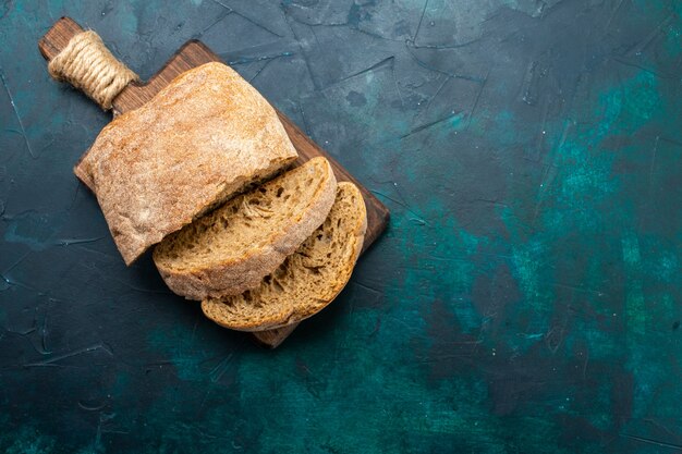 Буханки хлеба, вид спереди, вкусно испечены и нарезаны на темно-синем столе.