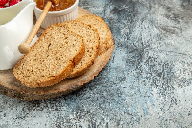 明るい表面の朝食用食品フルーツに蜂蜜とイチゴを添えた正面図のパン