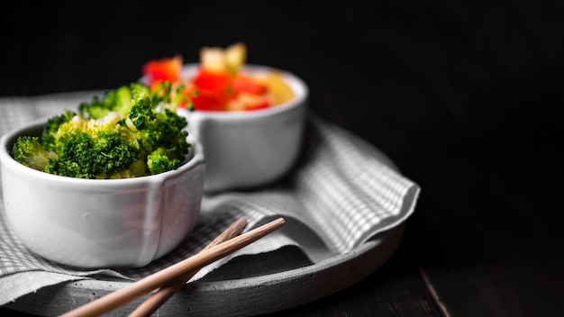 Front view of broccoli in cup with chopsticks and cloth