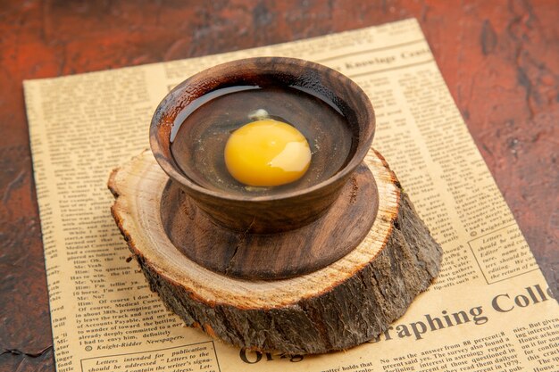 Вид спереди разбитое сырое яйцо внутри тарелки на темной поверхности