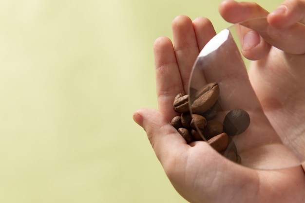 Free photo a front view brown coffee seeds in boys hands