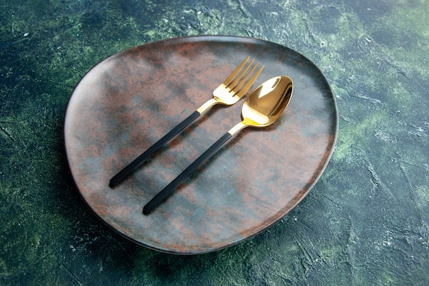 front view brown empty plate with golden spoon and fork on dark background