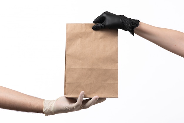 A front view brown paper package with food inside being delivered from female to male