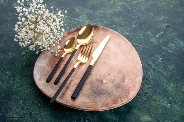 вид спереди коричневая тарелка с золотыми столовыми приборами на темно-синем фоне