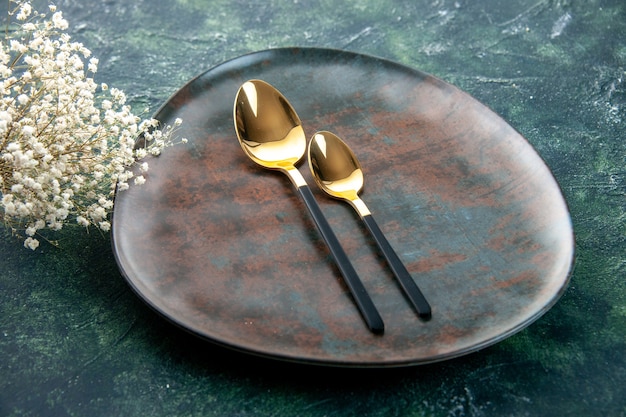 front view brown plate with golden spoons on a dark blue background