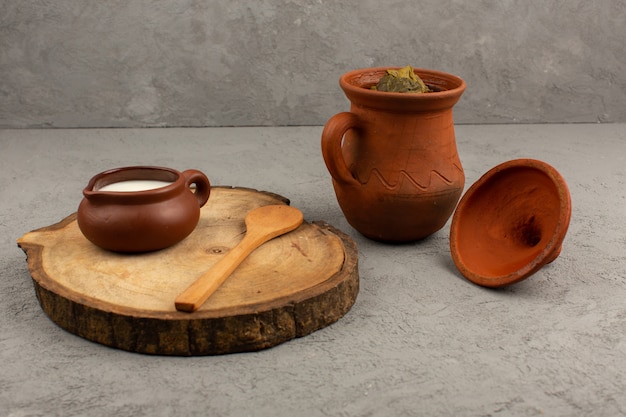 front view brown pots designed with dolma and yogurt on the grey floor