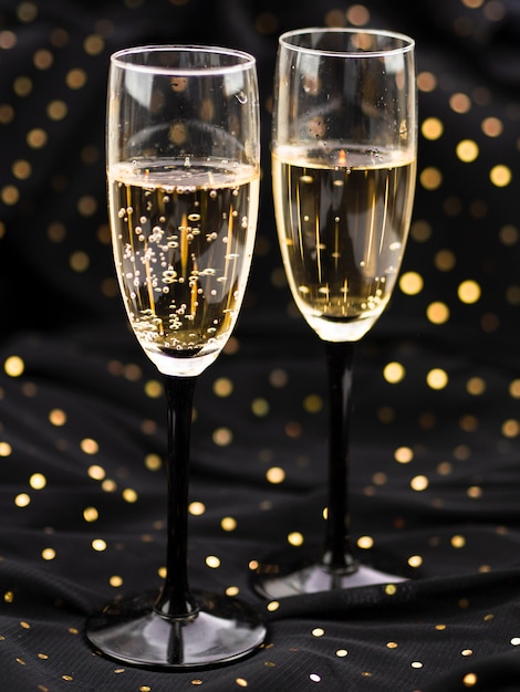 Front view of bubbly glasses of champagne with golden dots