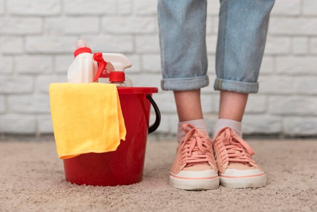 Front view of bucket with cleaning supplies next to woman