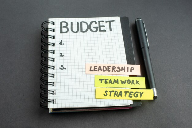 бюджетная записка вид спереди в блокноте с ручкой на темном фоне