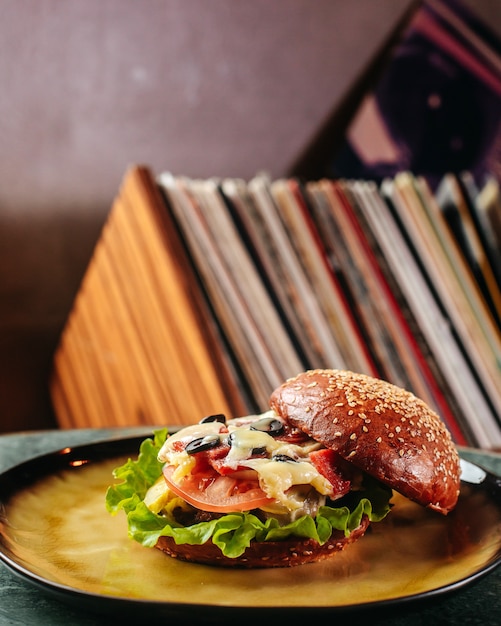 A front view burger tasty with vegetables and meat inside round plate