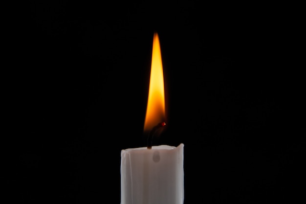 Front view burning candle on dark surface