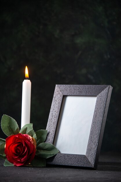 Front view of burning candle with picture frame on dark surface