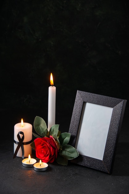 Front view burning candle with picture frame and flower on dark surface