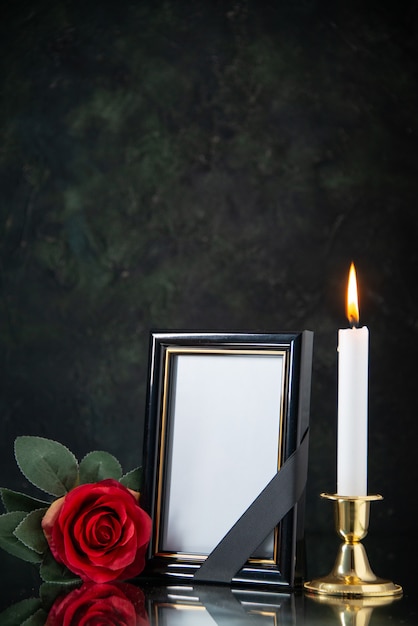 Вид спереди горящей свечи с красным цветком на черной поверхности