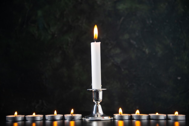 Вид спереди горящих свечей как память о упавших на черную поверхность