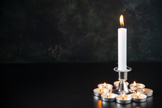 Front view of burning candles as memory for fallen on the black surface