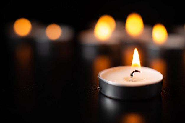 Front view of burning candles on pitch black surface