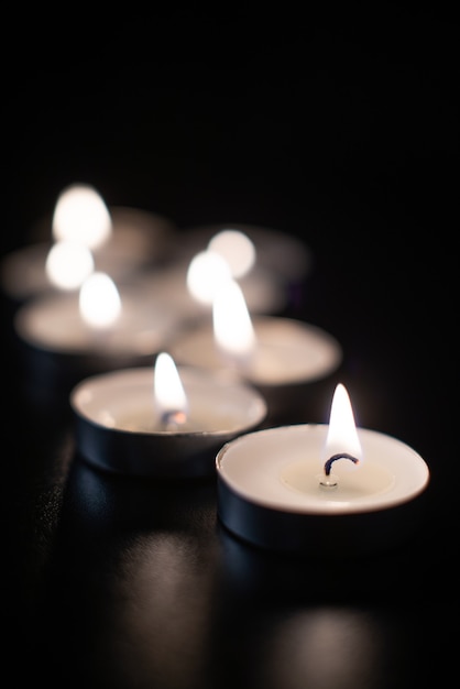 Front view of burning candles on pitch black surface