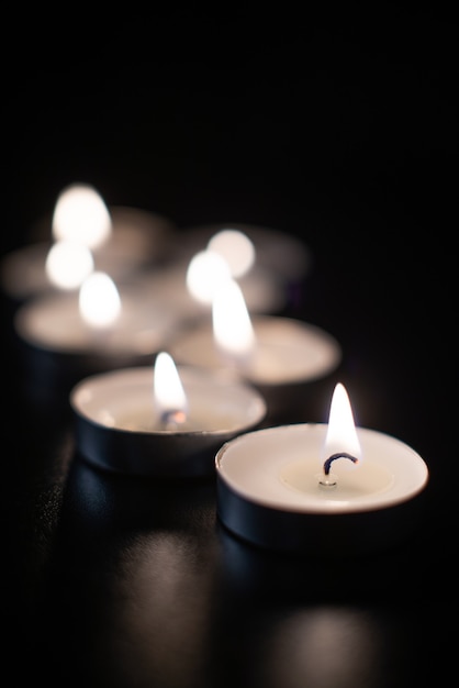 Вид спереди горящих свечей на черной как смоль поверхности