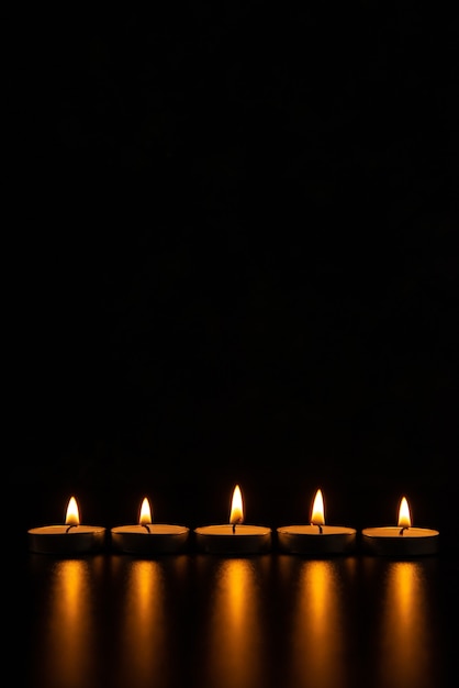 Free photo front view of burning candles on the pitch black surface