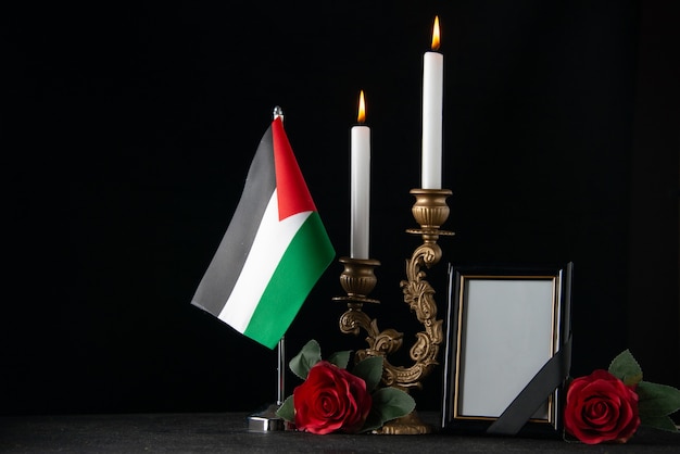 Вид спереди горящие свечи с палестинским флагом и темной поверхностью фоторамки