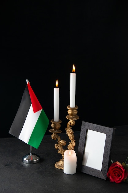 Front view of burning candles with picture frame on dark surface