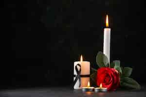Foto gratuita vista frontale di candele accese con fiore rosso sulla superficie scura