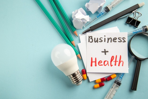 бизнес-здоровье вид спереди с таблетками, карандашами и инъекциями на синем фоне