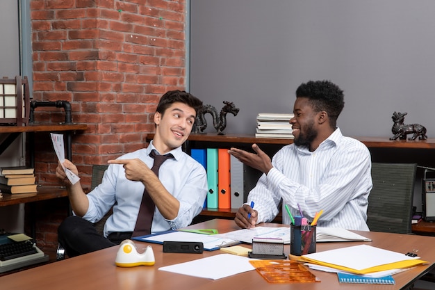 Front view business negotiations two businessmen talking to each other while one of them pointing at paper