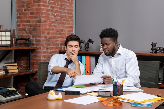 Front view business negotiations two workmates sitting at desk and talking about a project