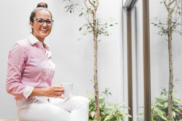 Free photo front view business woman sitting on a stool